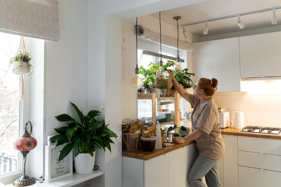 Woman placing plants on a shelf in a kitchen