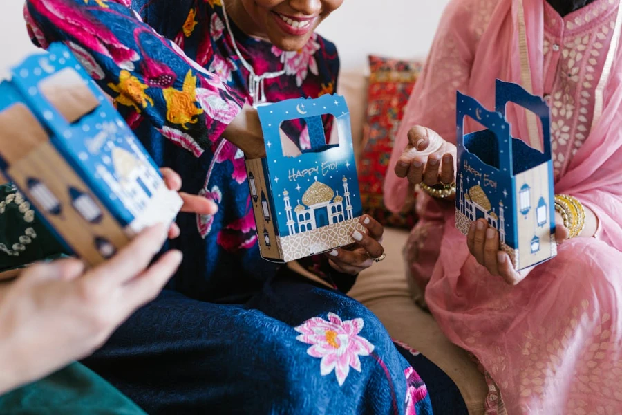 Women holding Eid-themed cardboard boxes