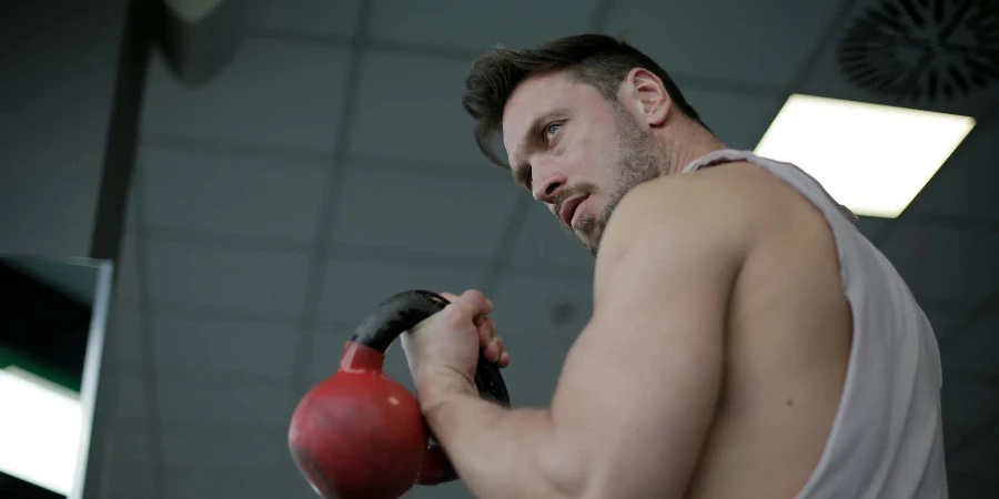 Strong confident sportsman during training with kettlebell in gym
