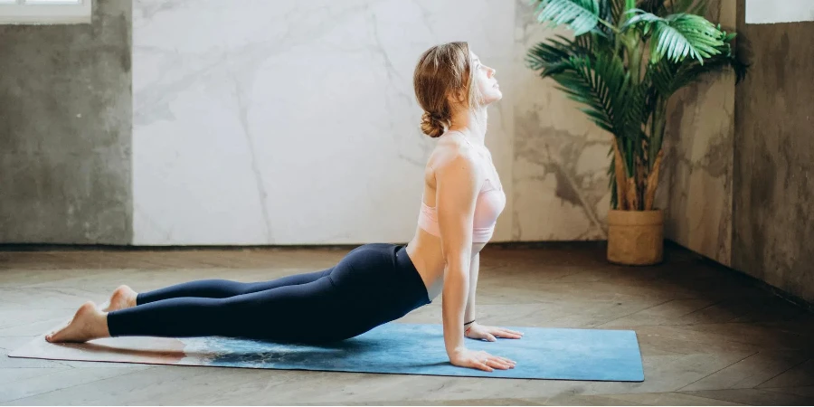 Woman in Pink Sports Bra and Black Leggings Doing Yoga on Yoga Mat