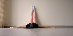 Woman laying on floor relaxing feet up on wall background