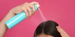 Young woman applying dry shampoo