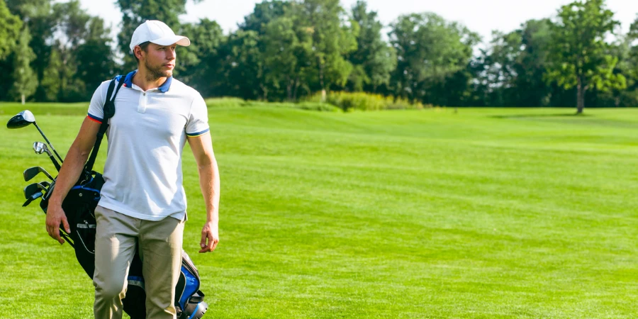young male golfer carries a bag of golf clubs