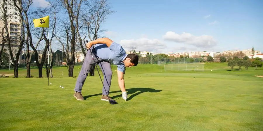 A Man Bending Forward while Holding a Golf Club by Kampus Production