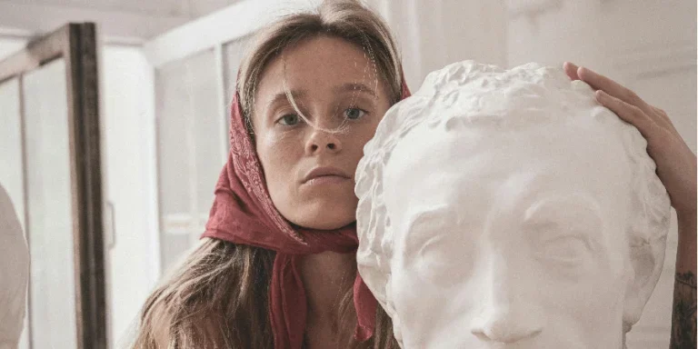 A Woman Hugging a Head Bust Sculpture