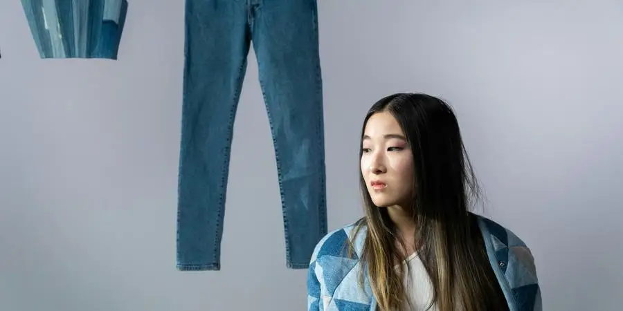 A Woman Standing Near Hanged Denim Pants and Crop Top by cottonbro studio