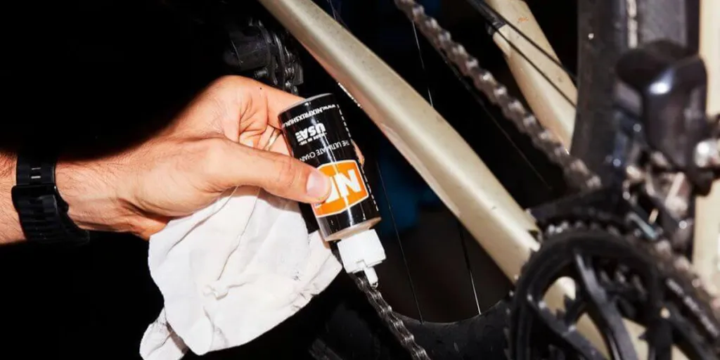 A biker applying lube on a bike chain