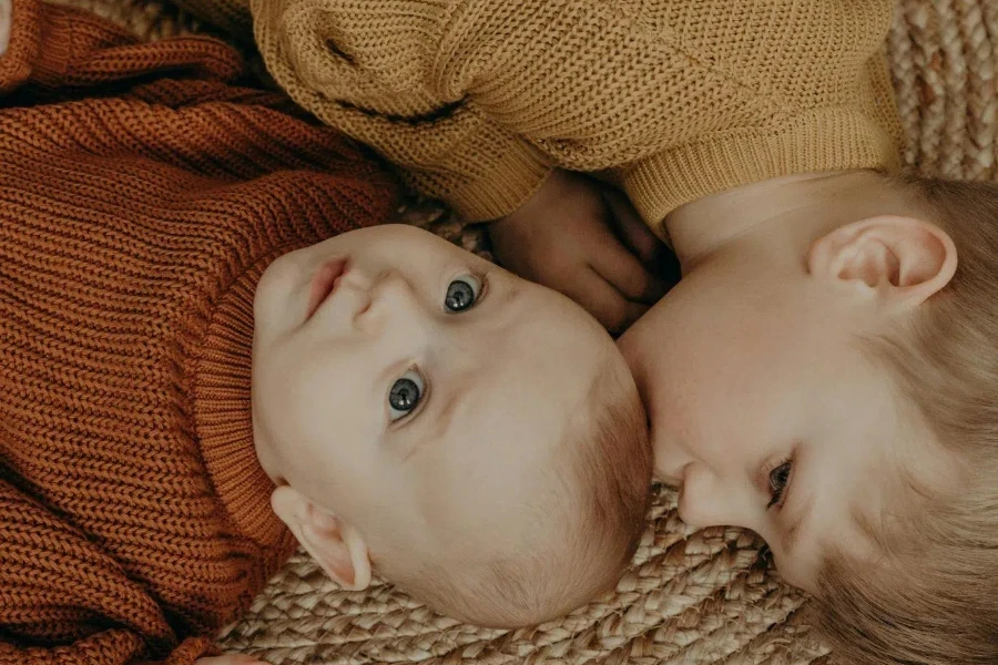 A boy in knitwear kissing a baby