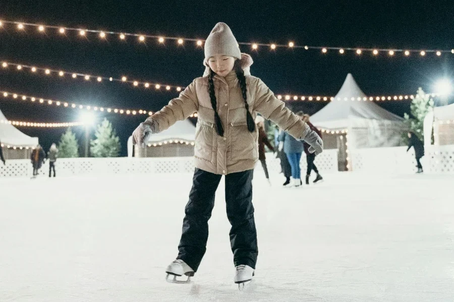 A girl wearing brown dawn jacket skating on ice rink