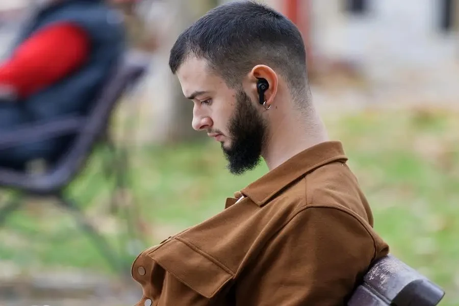 A man sitting in the park wearing True Wireless Earbuds