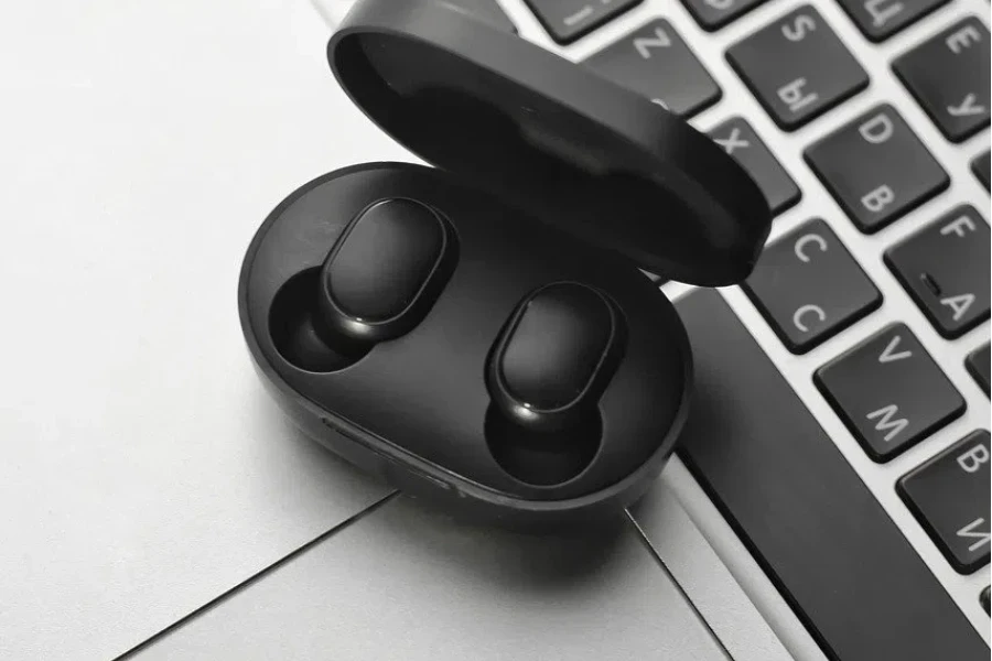 A pair of True Wireless Earbuds are placed next to the keyboard