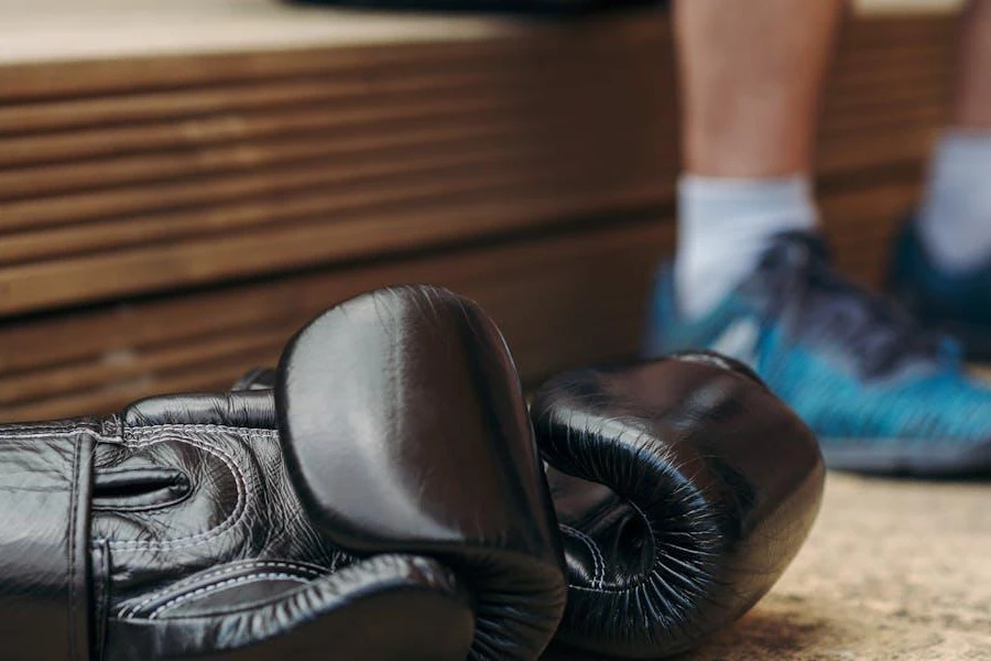 A pair of black boxing gloves near a person's feet