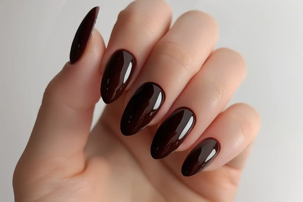 A photo of the hand with dark brown oval nails