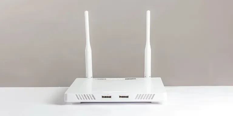 A white router with two antennas and one antenna on the side