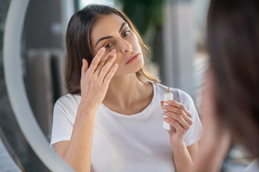 A woman appying a concealer to her skin 