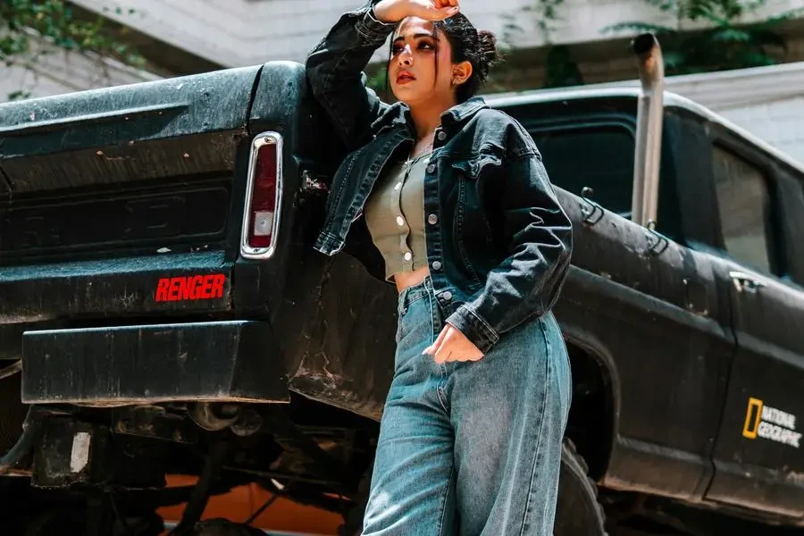 A woman in denim pants and a jacket standing next to a truck by Amirali Shaghaghi