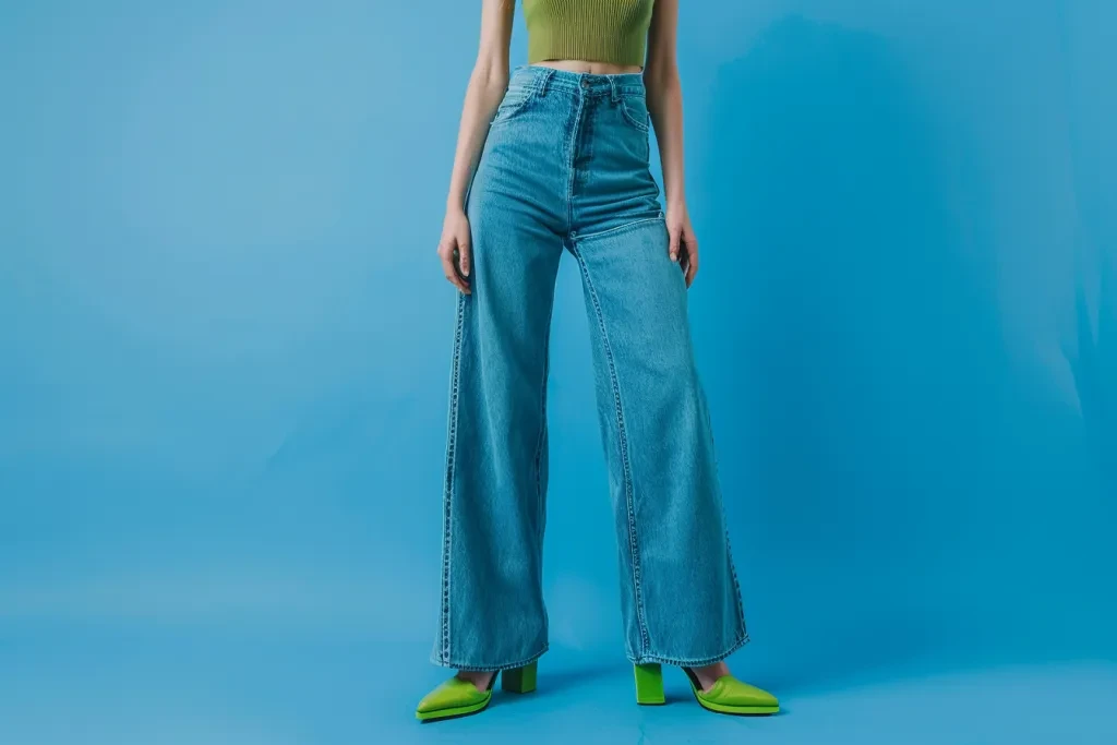 A woman in jeans and a green top stands on a blue background