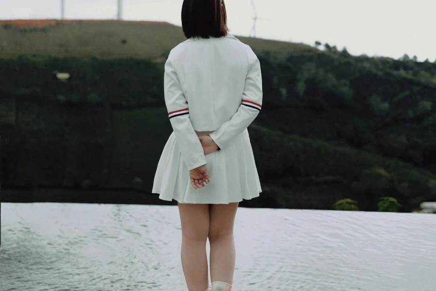 A woman in white dress standing near wind turbines