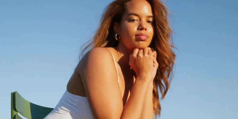 Una mujer sentada en un banco del parque con las manos en el regazo.