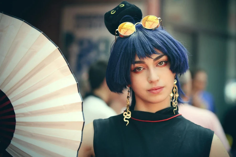 A woman with blue hair and a black and white fan