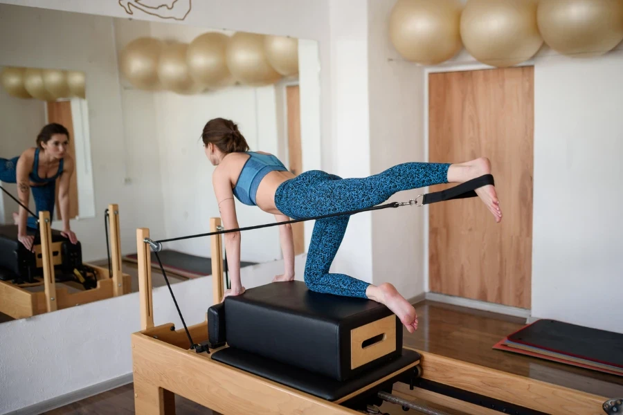 A young woman in sportswear does Pilates on a reformer