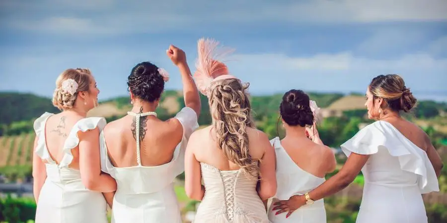 Anonymous bridesmaids and bride on hill near plants and trees by X L