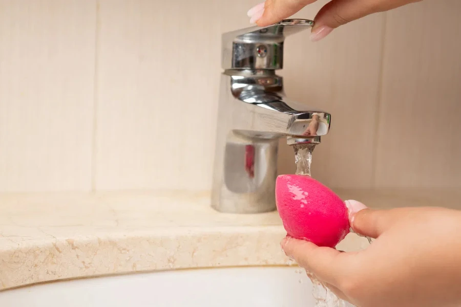 Beautician cleansing beauty blender after applying makeup