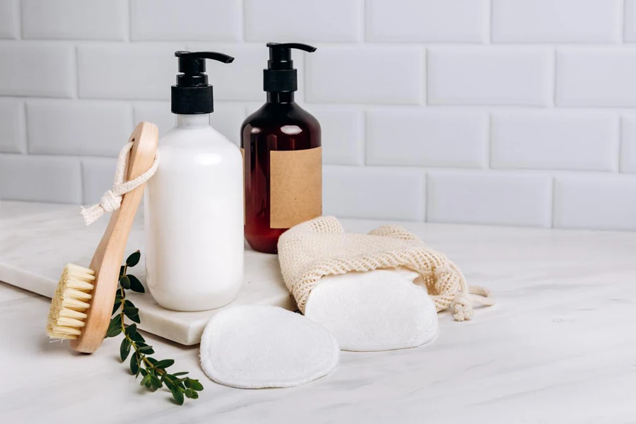 Bottles of shampoo, soap, shower gel, moisturizer, makeup remover and cotton reusable makeup remover pads