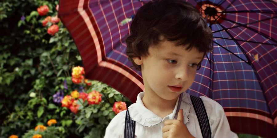 Menino segurando guarda-chuva roxo