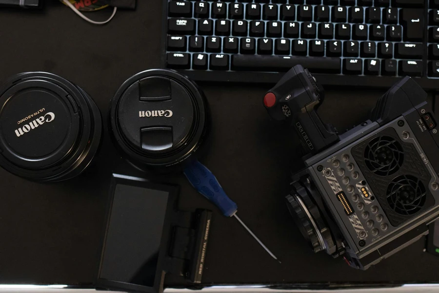 Canon Camera Lens Covers Beside Screwdriver and Computer Keyboard