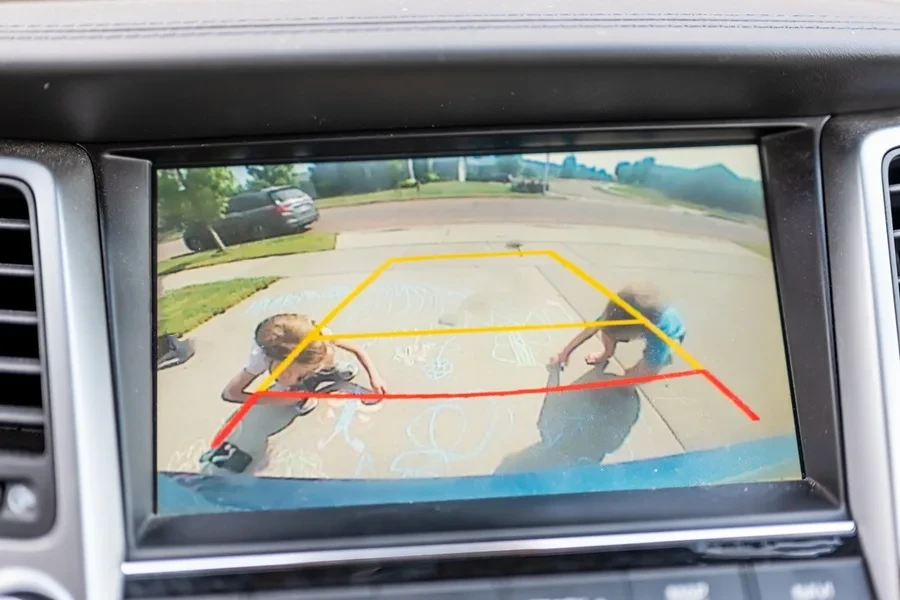 Children seen in a rear view backup camera drawing with chalk.