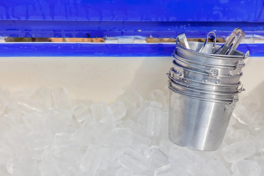 Clear ice cubes keep in big plastic tank and small metal buckets ready to serve in restaurant