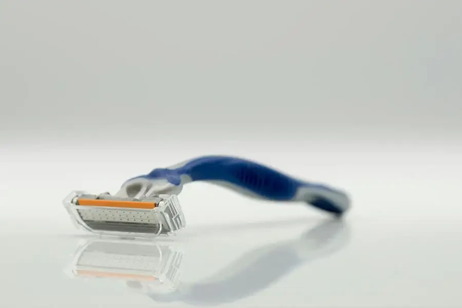 Close-Up Photo of a Blue and Gray Razor on a White Surface by Robert Golebiewski