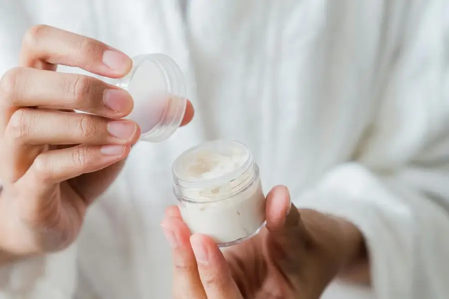 Close-Up Shot of a Person Holding a Moisturizer by Greta Hoffman