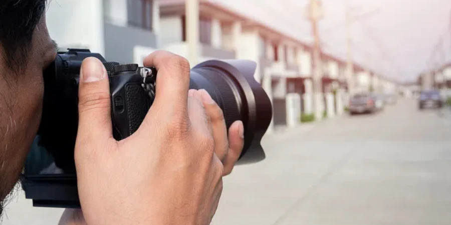 Nahaufnahme der Hände eines jungen asiatischen Fotografen, der Bilder von Wohnsiedlungen macht