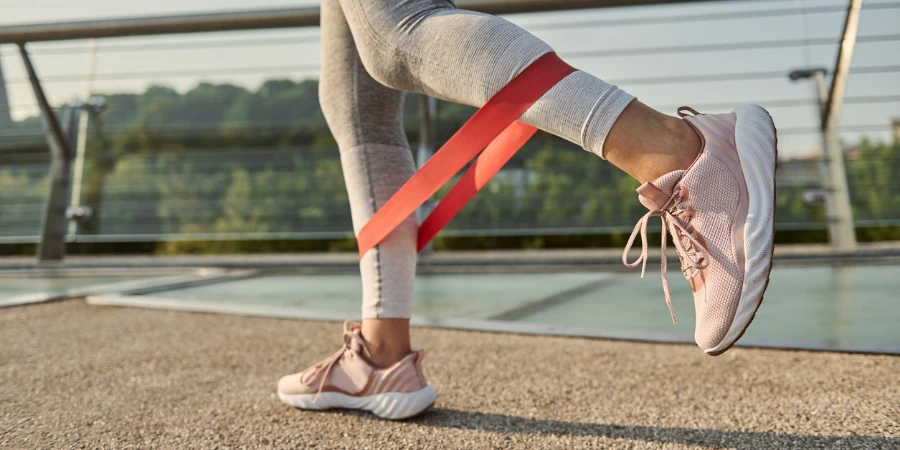 Close-up of the legs of an athlete woman doing body weight training with a resistance fitness elastic band on a city bridge