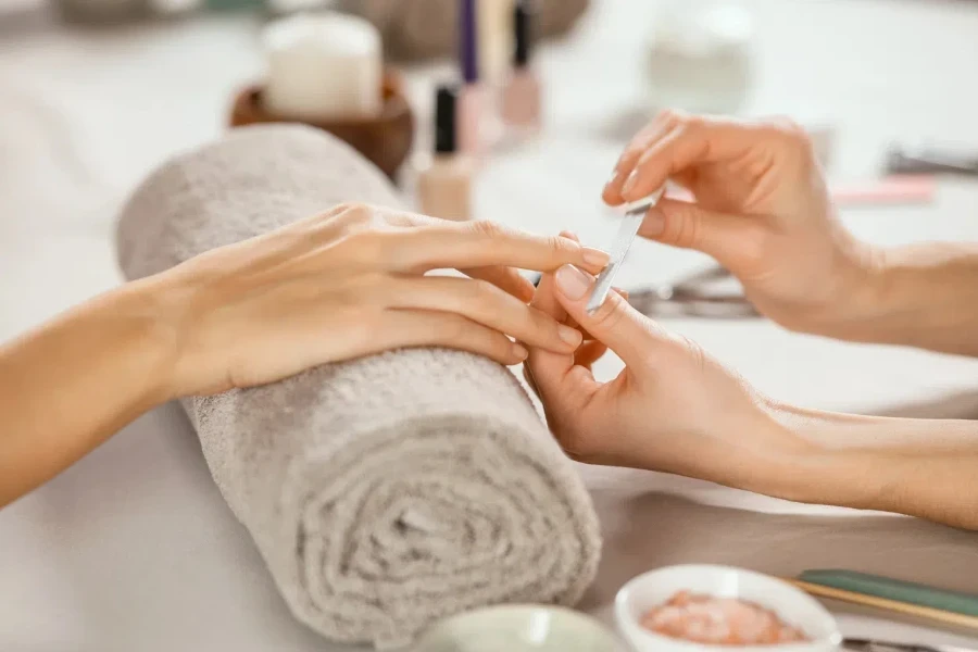 Close up shot of a woman in a nail salon receiving manicure by beautician