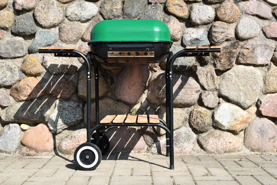 Closed grill with green lid outdoors on grey brown stone wall background.