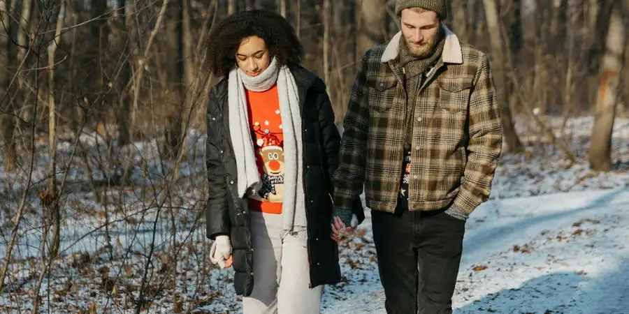 Couple Walking on Snow Covered Ground Near Trees by Polina Kovaleva