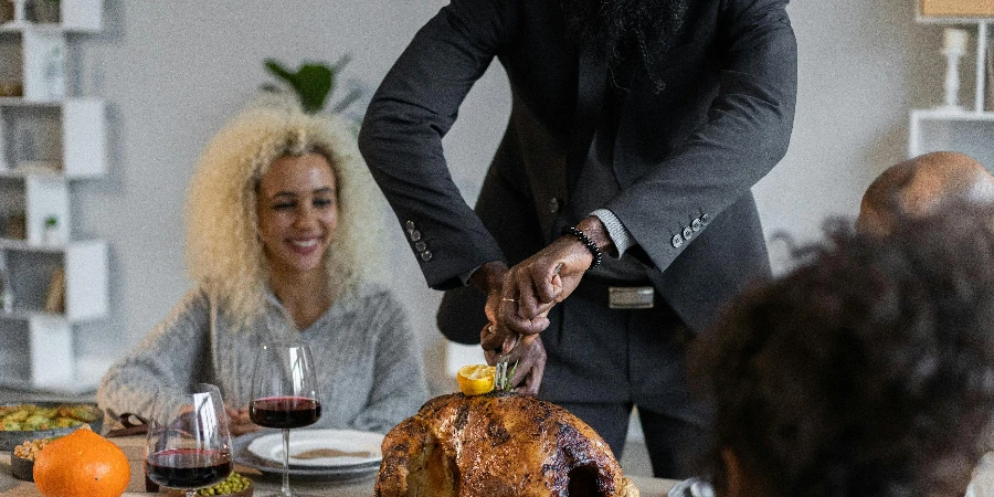 Crop black man in suit cutting roasted turkey