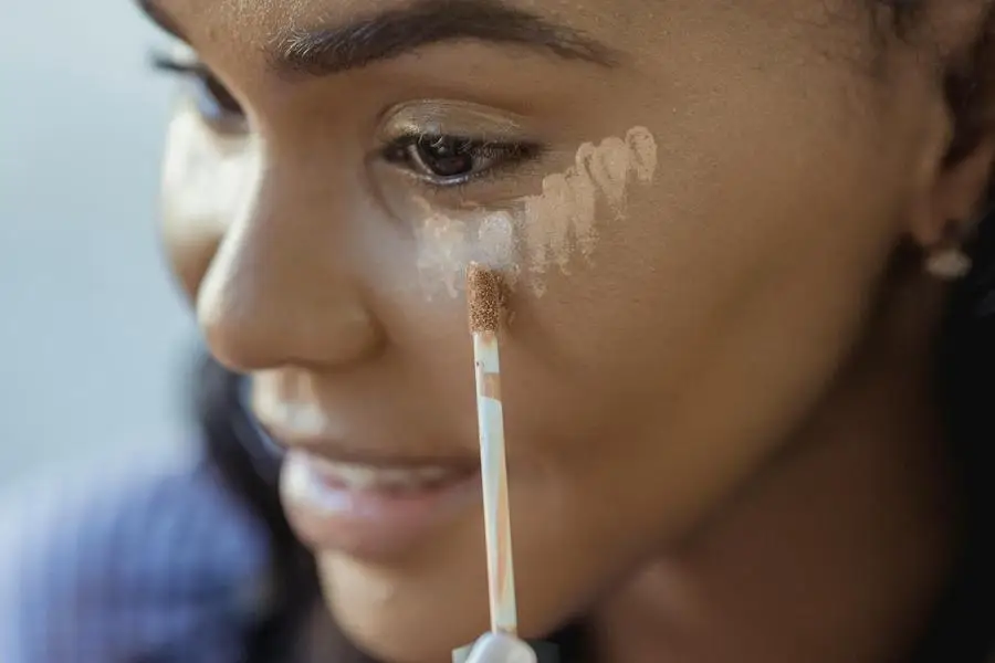 Crop black woman applying concealer on face by George Milton