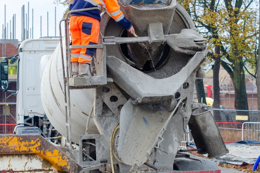 Delivery driver washing concrete vagon after delivering concrete on building site