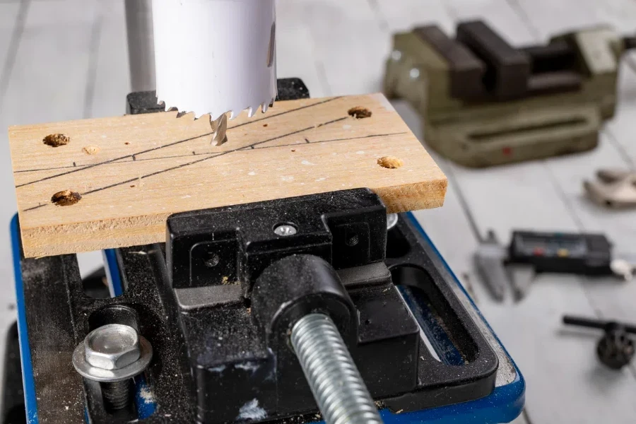 Drilling a large hole in wood. Hole saw used in a table drill