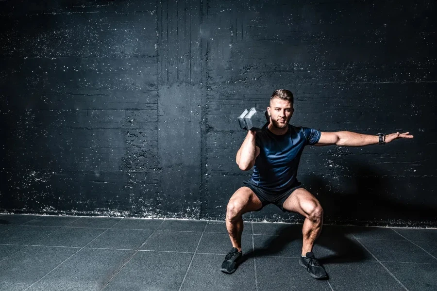 Dumbbells weight training, Young strong fit muscular sweaty man with big muscles strength cross workout training with dumbbells weights in the gym dark image with shadows real people 