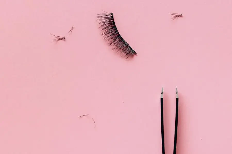 False Eyelashes Beside the Tweezers on Pink Surface by Nataliya Vaitkevich