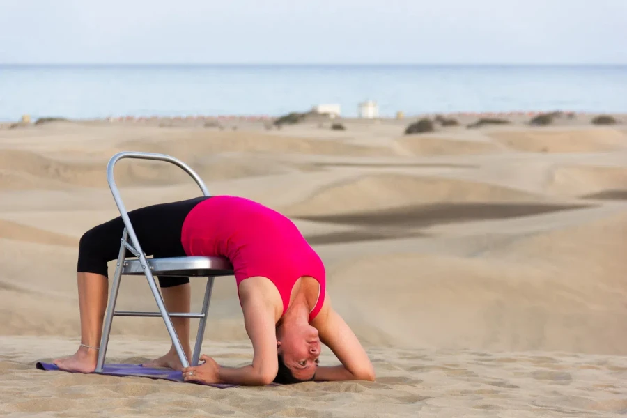 Female yogi doing back bend exercise on chair outdoors in Canary Islands, Spain