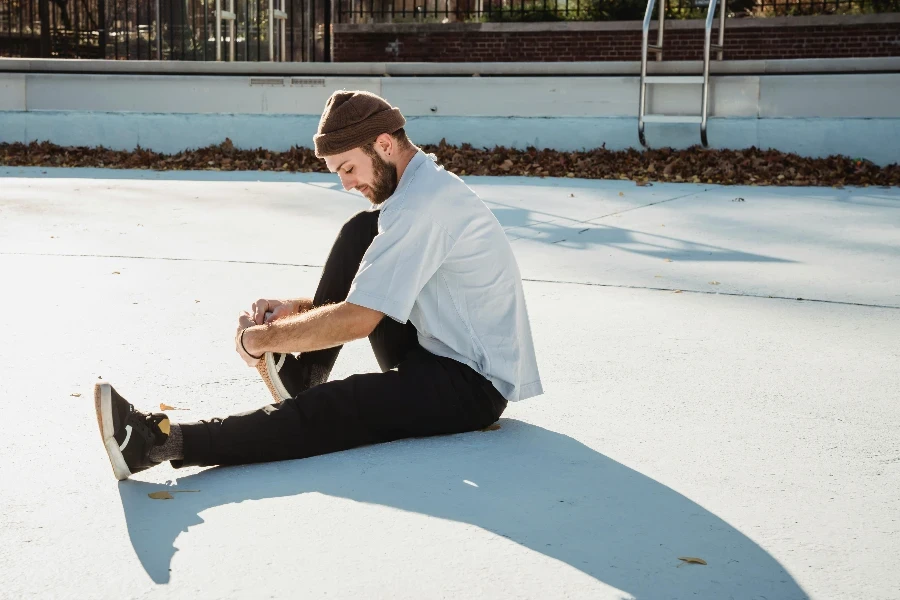 Fit sportsman stretching leg on street in sunlight