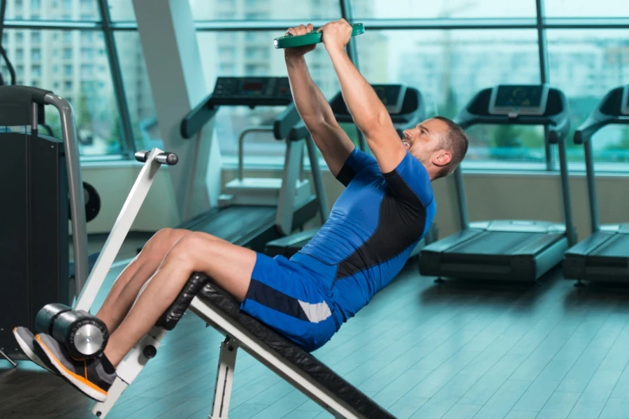 Fitness Man Working Out Abs With Weights On Adjustable Bench In Gym Center