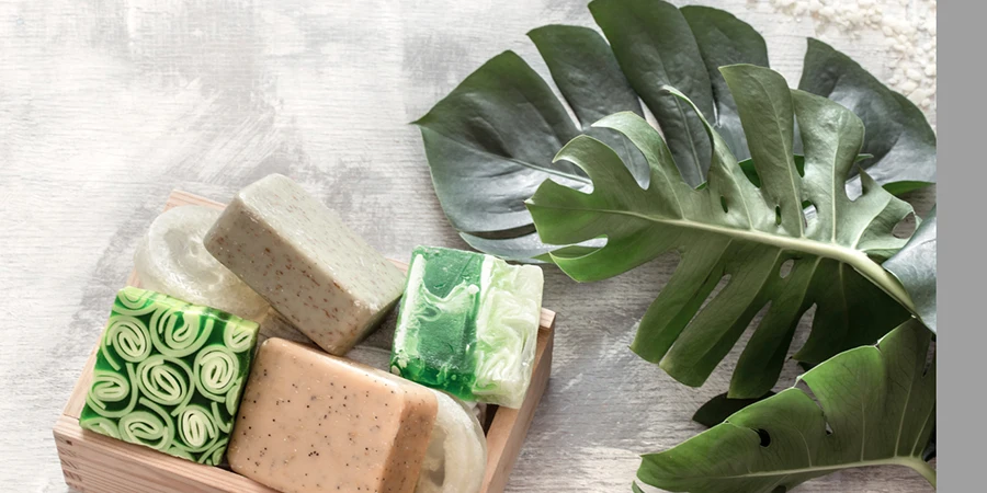 Flat-lay natural beautiful cosmetics handmade soap with tropical leaves on a light background, top view