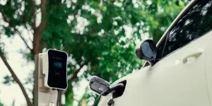 Fokuskan mobil EV closeup dan pengisi daya dengan latar belakang buram untuk konsep progresif